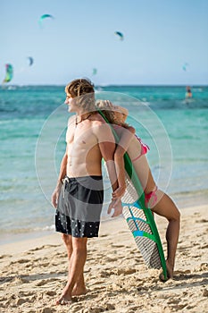 Young couple on beach with surfboard in arm. Surfing and outdoor sport lifestyle concept