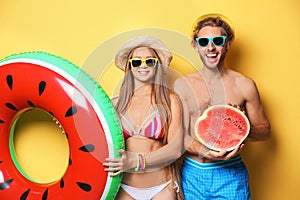 Young couple in beachwear with inflatable ring and watermelon