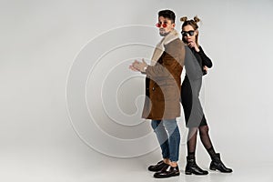 Young couple of bearded man in coat and pretty woman in black dress with long blonde hair