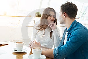 Young couple beautiful woman and handsome man drinking coffee in cafe looking at each other, love and tenderness concept