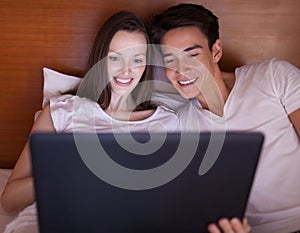 Young couple in bed with laptop