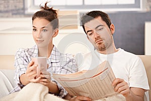 Young couple in bed man reading woman drinking tea