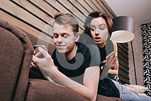 Young couple in bed with smartphone in hands