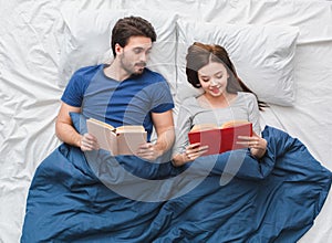 Young couple in bed top view morning concept reading novel