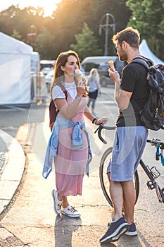 young couple with bicycle and backpacks eating ice cream