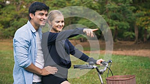 Young couple with bicycle walking in park on sunny day