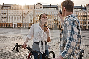 Young couple with bicycles drinking coffee in city