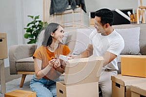 Young couple with big boxes moving into a new house, new apartment for couple, young asian man and woman helping to lift boxes on