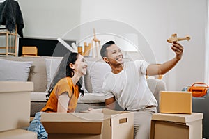 Young couple with big boxes moving into a new house, new apartment for couple, young asian man and woman helping to lift boxes on