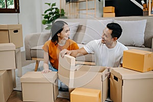 Young couple with big boxes moving into a new house, new apartment for couple, young asian man and woman helping to lift boxes on