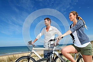 Young couple biking by the beach