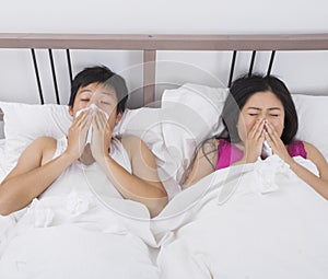 Young couple blowing noses in bed