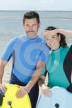 young couple bodyboard surfers looking at camera