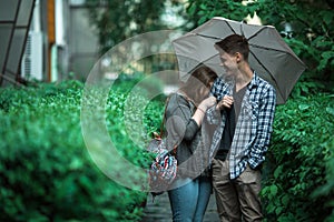 Young couple boy and girl standing under an umbrella on the street.