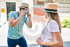 Young couple of boyfriend and girlfriend tourists on a summer trip taking pictures using vintage camera