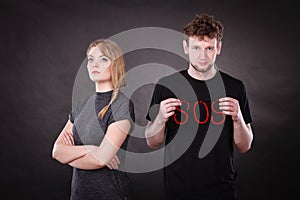 Young couple with broken heart and sos word.
