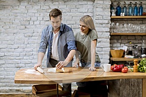 Young couple caking pizza in kitchen together
