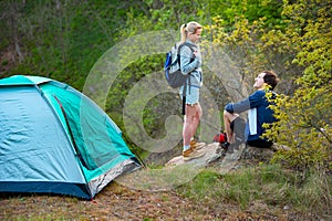 Young couple camping trip in forest at summer weekend. Travel, tourism, hike and people concept