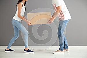 Young couple carrying big moving box at new home