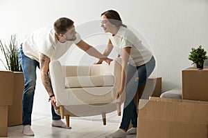 Young couple carrying chair together, placing furniture in new h