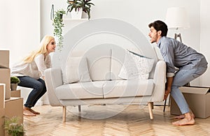 Young Couple Carrying Couch Into New Apartment On Moving Day