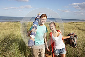 Young Couple Carrying Picnic Basket And Windbreak photo
