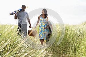 Young Couple Carrying Picnic Basket And Windbreak photo