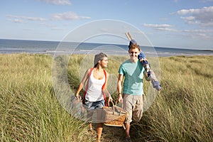 Young Couple Carrying Picnic Basket And Windbreak photo