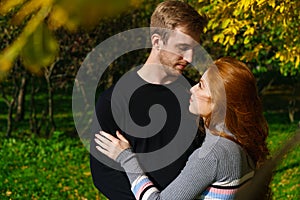 young couple are standing in an embrace in the park on a sunny day