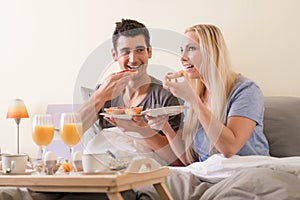 Young couple celebrating with breakfast in bed