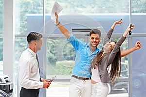 Young Couple Celebrating Purchase of a car In Car Showroom