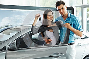 Young Couple Celebrating Purchase of a car In Car Showroom