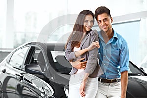 Young Couple Celebrating Purchase of a car In Car Showroom