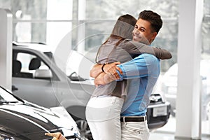 Young Couple Celebrating Purchase of a car In Car Showroom