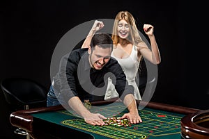 Young couple celebrating win at roulette table in casino.