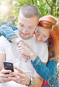 Young couple with cellphone at the park photo