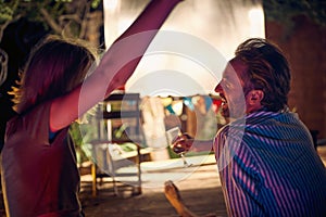 A young couple chatting while enjoying a night out in the bar at the river bank. Night, summer, bar, river