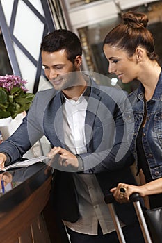 Young couple checking in at hotel reception