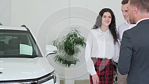 A young couple chooses a car in a modern car showroom.