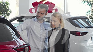 Young couple choosing automobile to buy at car dealership