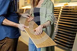 Couple choosing laminate floor design together for new house interior in flooring store photo