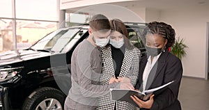 Young couple choosing new car for buying in dealership shop