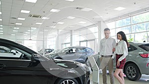 A young couple is choosing a new car at a dealership. Buying a car on credit