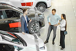 Young couple choosing new car in showroom. service, selling