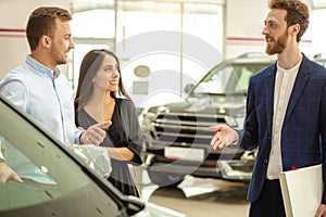 Young couple choosing new car in showroom. service, selling