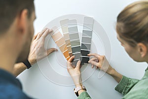 Young couple choosing paint color from samples for new home interior