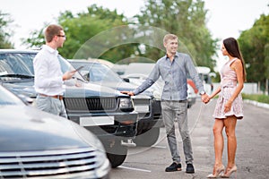 A young couple is choosing a used car. Used car theme.