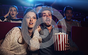 Young couple at the cinema watching an horror movie