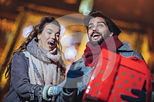 Young couple in the city centre with holiday`s brights in background.