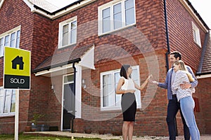 Young Couple Collecting Keys To New Home From Realtor